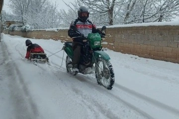 Motosiklete bağladığı kızaklarla evlatları karda eğlendirdi
